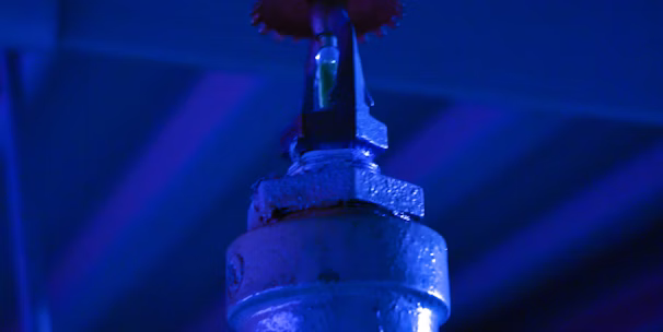 A vigilant firefighter in full gear inspecting a sprinkler system in an industrial setting.